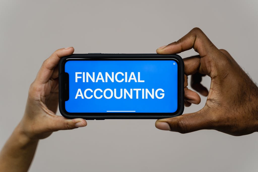 Close-up of hands holding smartphone displaying 'Financial Accounting'.